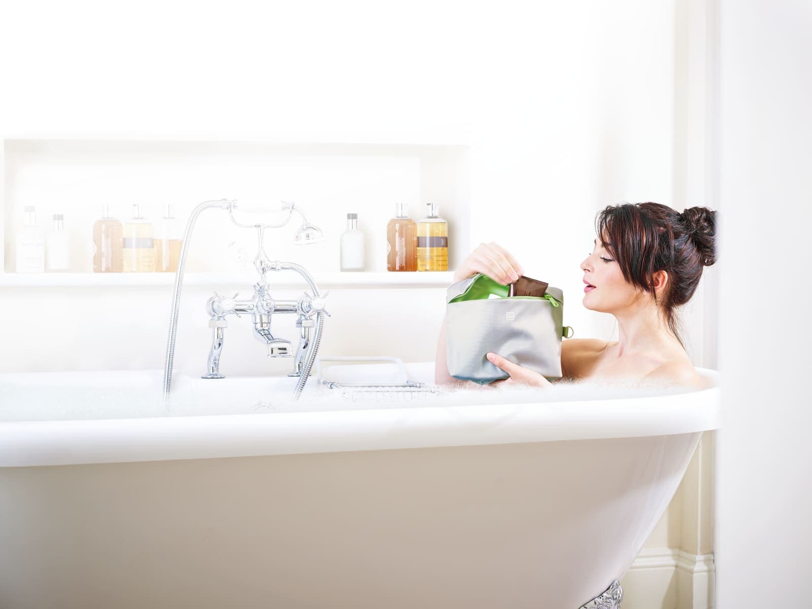 Woman in bath with GO TRAVEL wash bag
