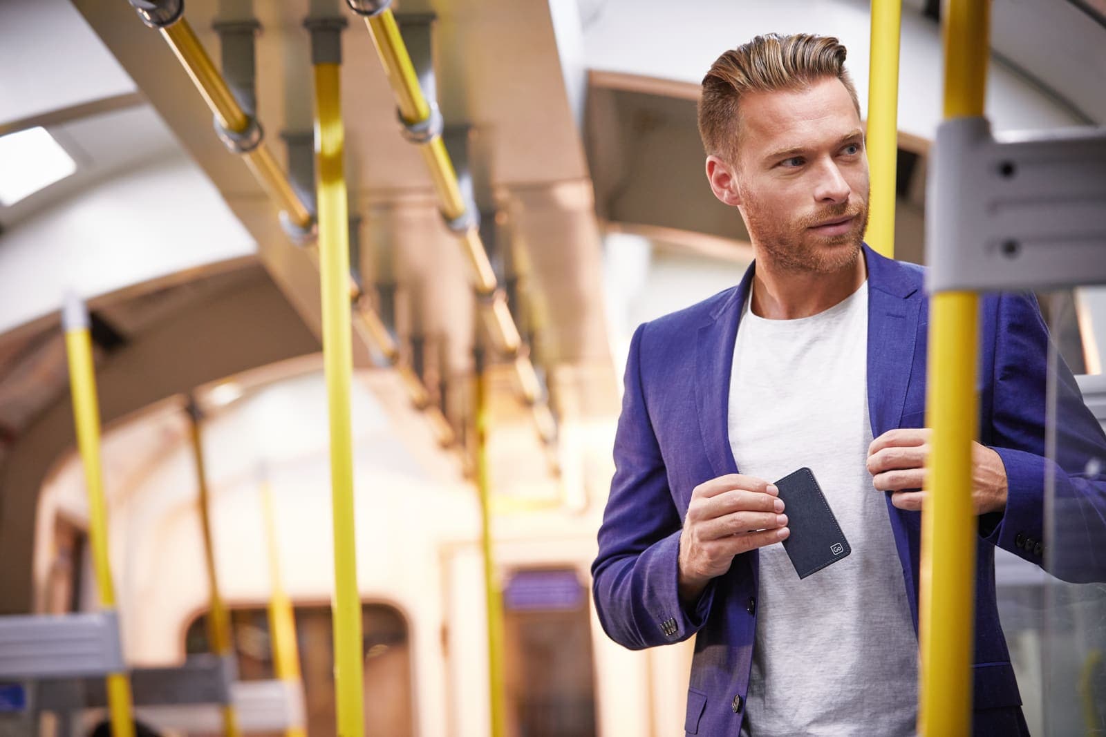 Man on public transport putting a dark grey RFID card slip into his blazer pocket.