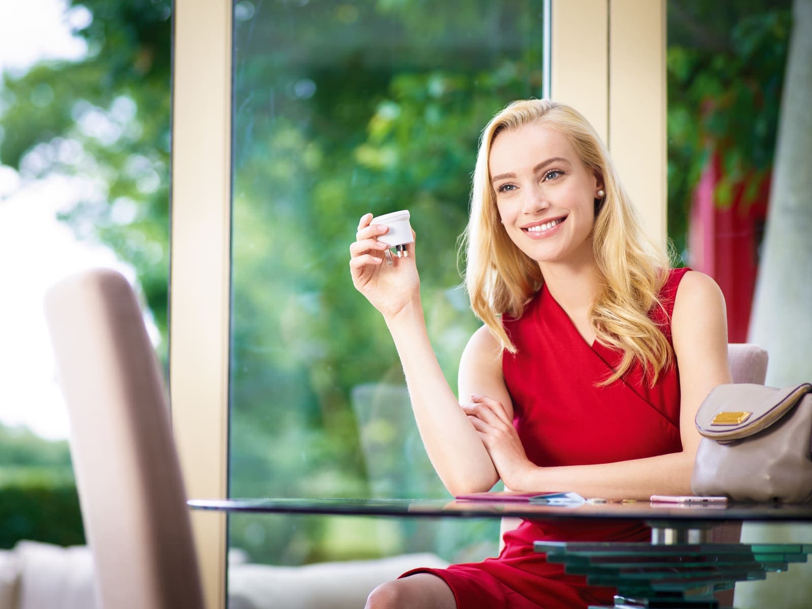 Woman in red dress holding a white GO TRAVEL EU-UK adapter.
