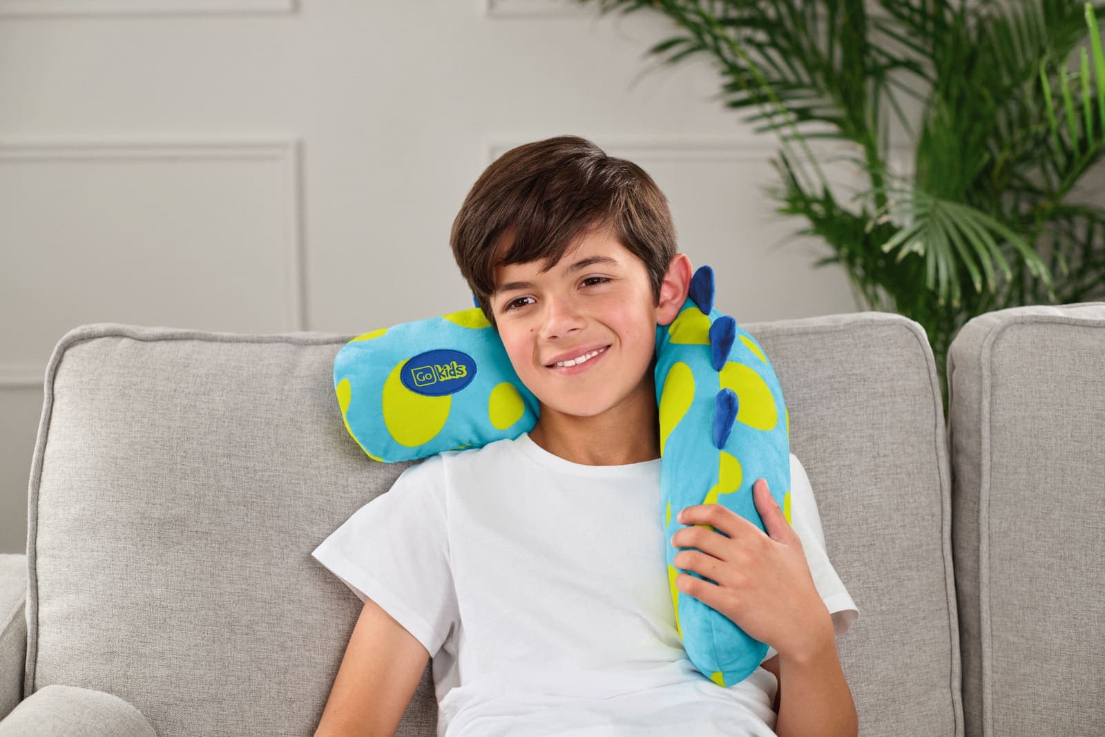 Boy wearing a blue and yellow monster travel pillow.