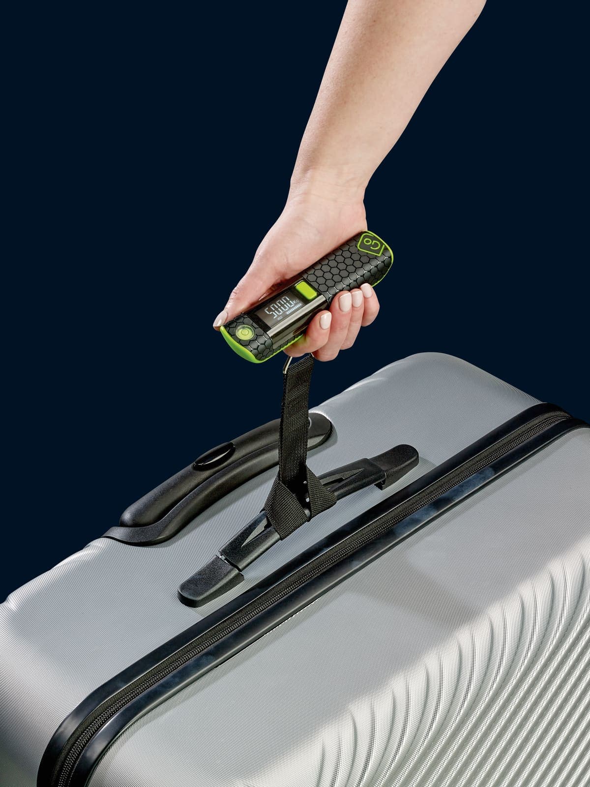 Hand holding GO TRAVEL Digital Scale Pro to weigh a suitcase.