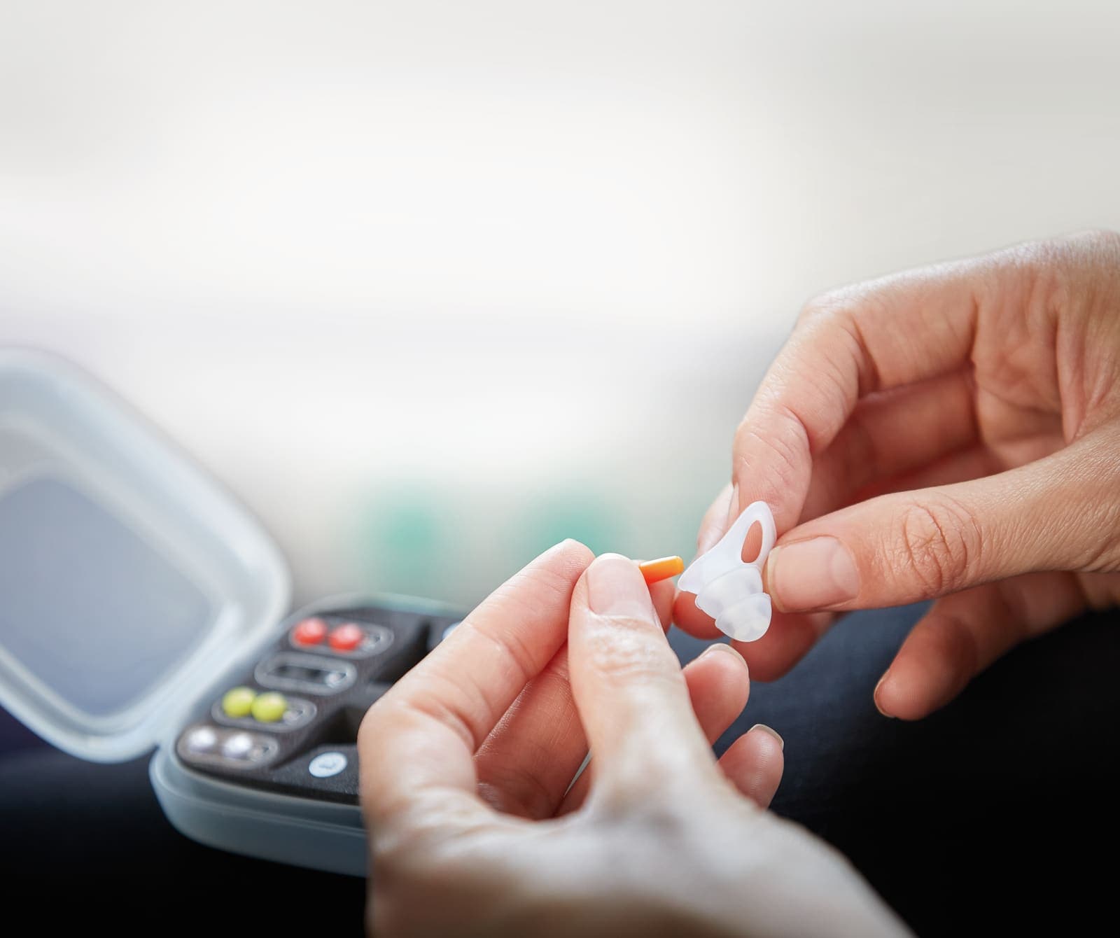 Hands holding GO TRAVEL earplugs and a pill organizer.